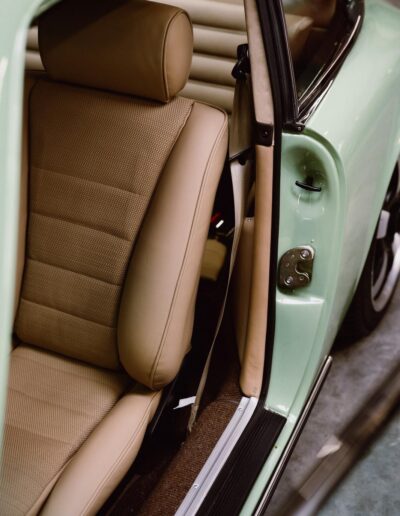 Tan leather seat beside the open door of a green Revolt Electric